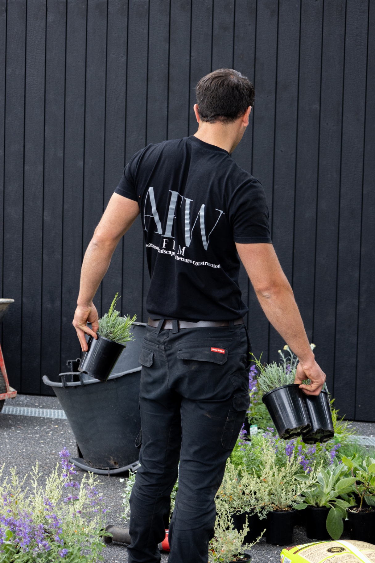 AFW Firm staff sorting plant stock against a charcoal timber facade